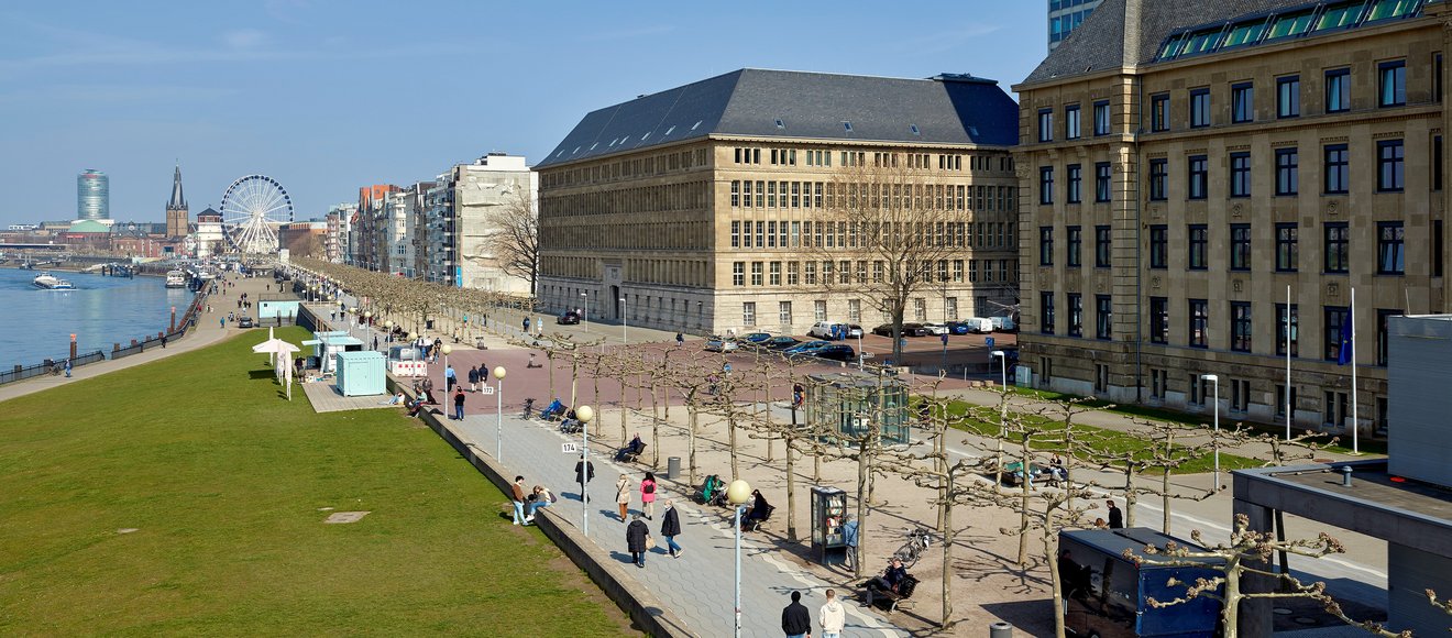 Blick auf das Rheinufer mit dem Behrensbau auf der rechten Seite. 